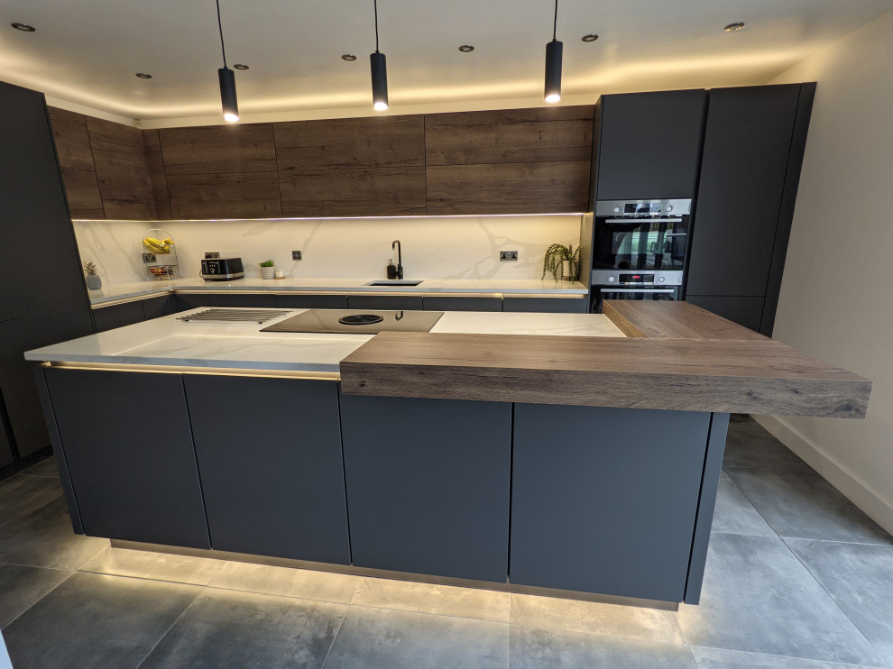 Design ideas for a medium sized contemporary cream and black enclosed kitchen in Other with a built-in sink, all styles of cabinet, black cabinets, quartz worktops, white splashback, black appliances, porcelain flooring, an island, grey floors, white worktops, all types of ceiling and feature lighting.