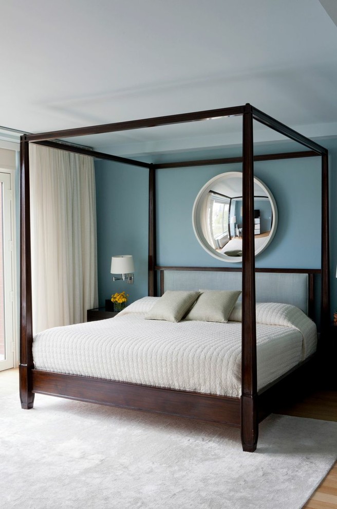 This is an example of a mid-sized contemporary master bedroom in New York with blue walls and light hardwood floors.