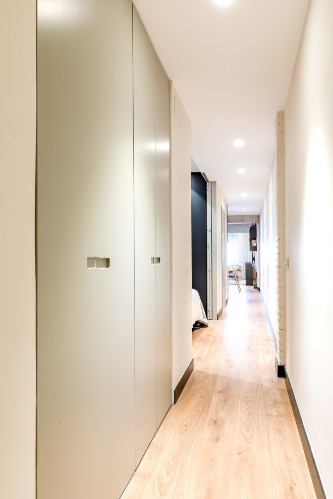 Photo of a small industrial hallway in Madrid with beige walls, medium hardwood floors and brown floor.