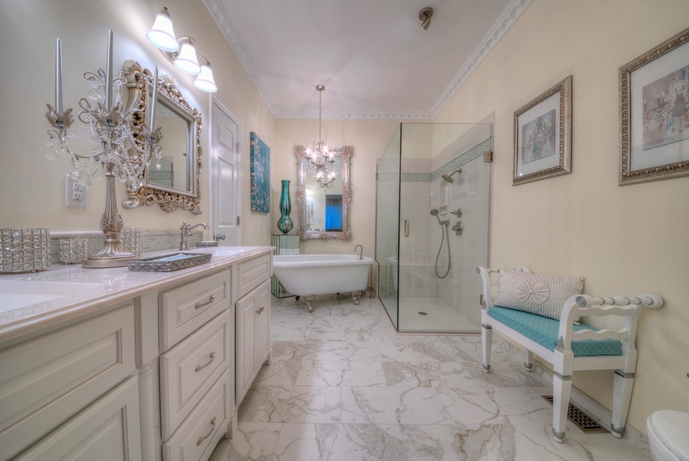 This is an example of a large traditional master bathroom in St Louis with raised-panel cabinets, white cabinets, a freestanding tub, a curbless shower, a two-piece toilet, yellow walls, porcelain floors, an integrated sink, onyx benchtops, multi-coloured floor and a hinged shower door.