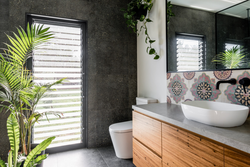 Cette image montre une salle de bain design en bois brun avec un placard à porte plane, un mur gris, une vasque, un sol gris, un plan de toilette gris et meuble simple vasque.