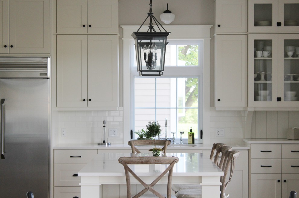 Inspiration for a large transitional l-shaped eat-in kitchen remodel in Toronto with an undermount sink, shaker cabinets, white cabinets, quartz countertops, white backsplash, stainless steel appliances and an island