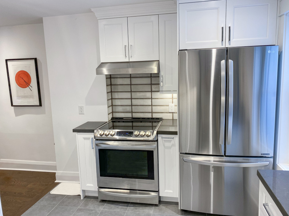 Small contemporary l-shaped eat-in kitchen in Toronto with an undermount sink, shaker cabinets, white cabinets, quartz benchtops, brown splashback, ceramic splashback, stainless steel appliances, porcelain floors, grey floor and grey benchtop.