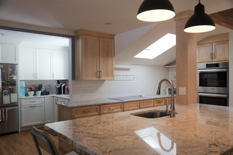 This is an example of a large traditional l-shaped eat-in kitchen in Boston with an undermount sink, recessed-panel cabinets, light wood cabinets, granite benchtops, white splashback, ceramic splashback, stainless steel appliances, medium hardwood floors, with island and multi-coloured benchtop.