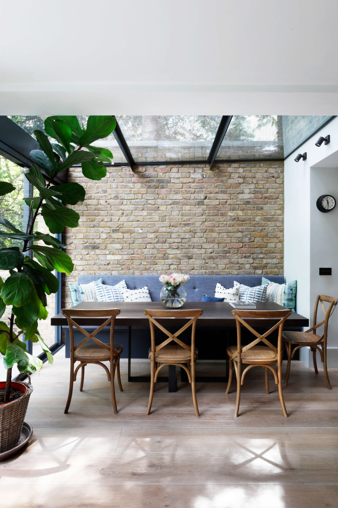 This is an example of a large contemporary kitchen/dining combo in London with white walls, medium hardwood floors, no fireplace, brown floor, coffered and brick walls.