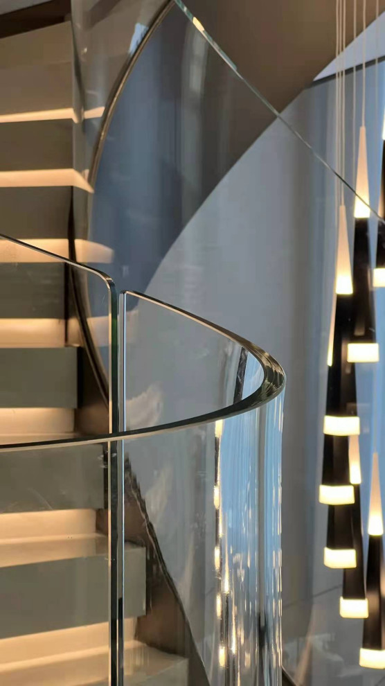 Diseño de escalera curva moderna grande con escalones de mármol, contrahuellas de mármol, barandilla de vidrio y ladrillo