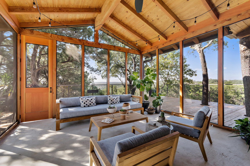 Contemporary screened-in verandah in Austin with concrete slab and a roof extension.
