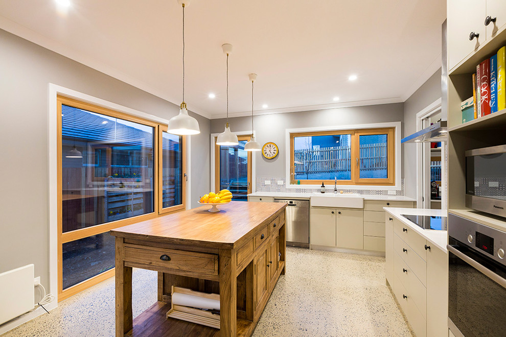 This is an example of a mid-sized traditional l-shaped eat-in kitchen in Canberra - Queanbeyan with a farmhouse sink, quartz benchtops, multi-coloured splashback, porcelain splashback, stainless steel appliances, concrete floors and with island.