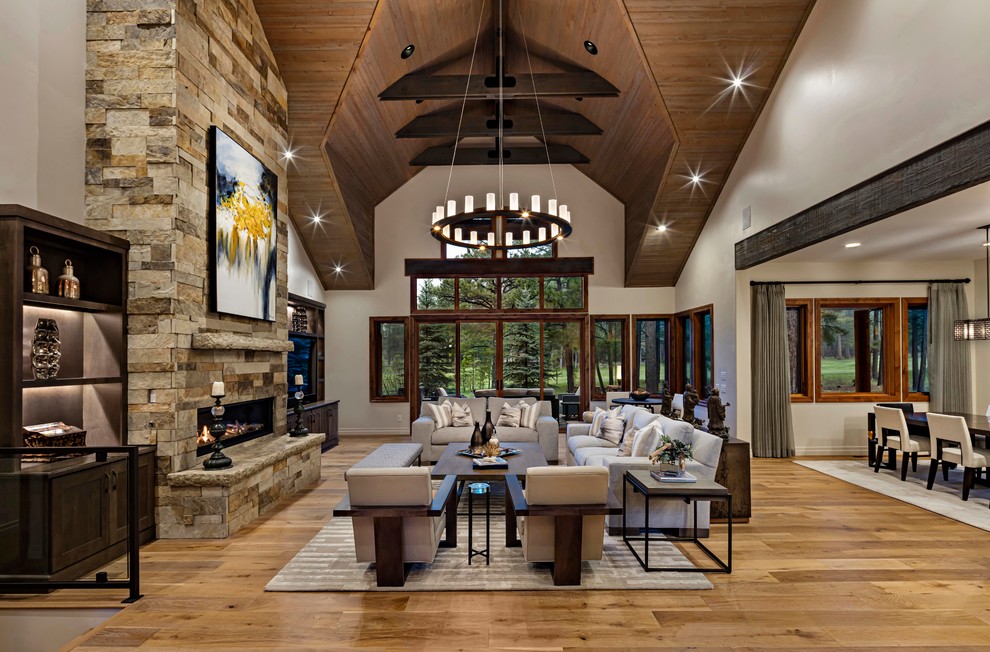 This is an example of a country open concept living room in Phoenix with white walls, medium hardwood floors, a ribbon fireplace, a stone fireplace surround, brown floor, a wall-mounted tv and vaulted.