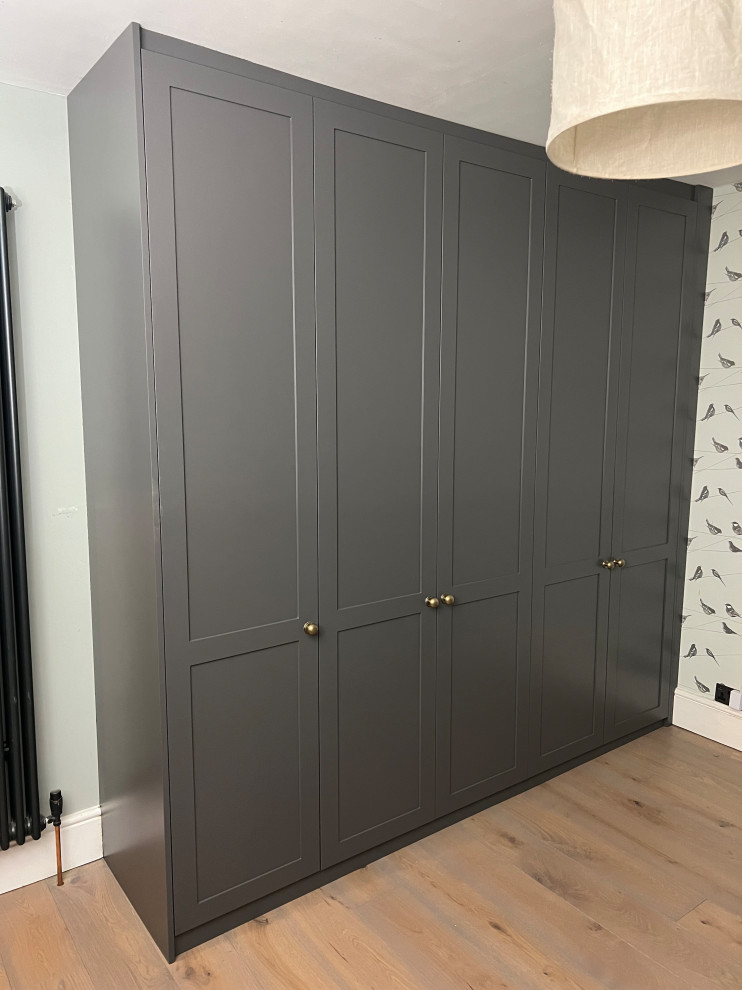 Inspiration pour une armoire encastrée traditionnelle de taille moyenne pour un homme avec un placard à porte shaker, des portes de placard grises et parquet clair.
