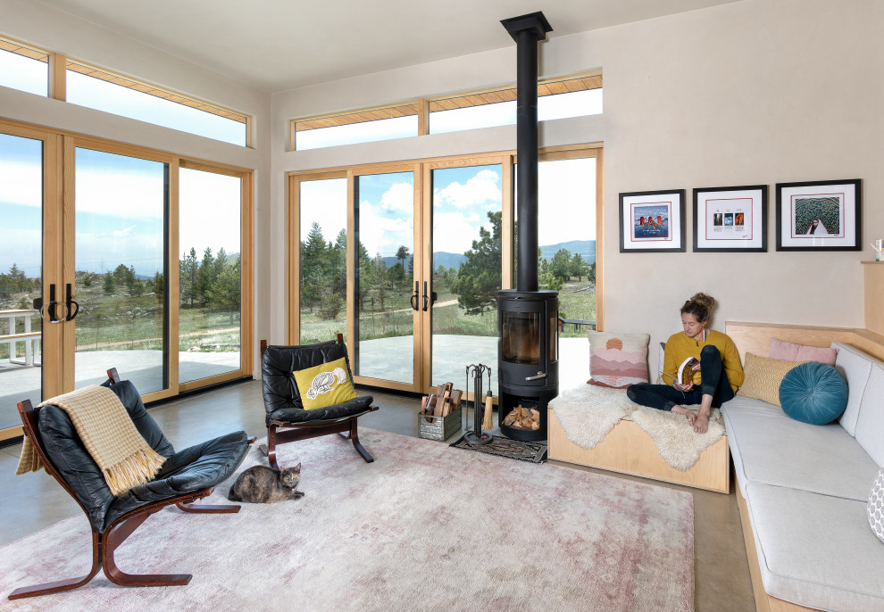 This is an example of a small country open concept living room in Denver with beige walls, concrete floors, a wood stove, no tv and brown floor.