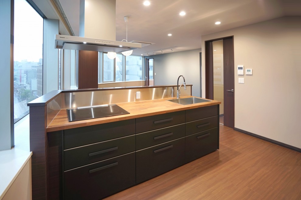 This is an example of a mid-sized modern single-wall open plan kitchen in Other with a single-bowl sink, recessed-panel cabinets, brown cabinets, plywood floors, with island, brown floor, brown benchtop and wallpaper.