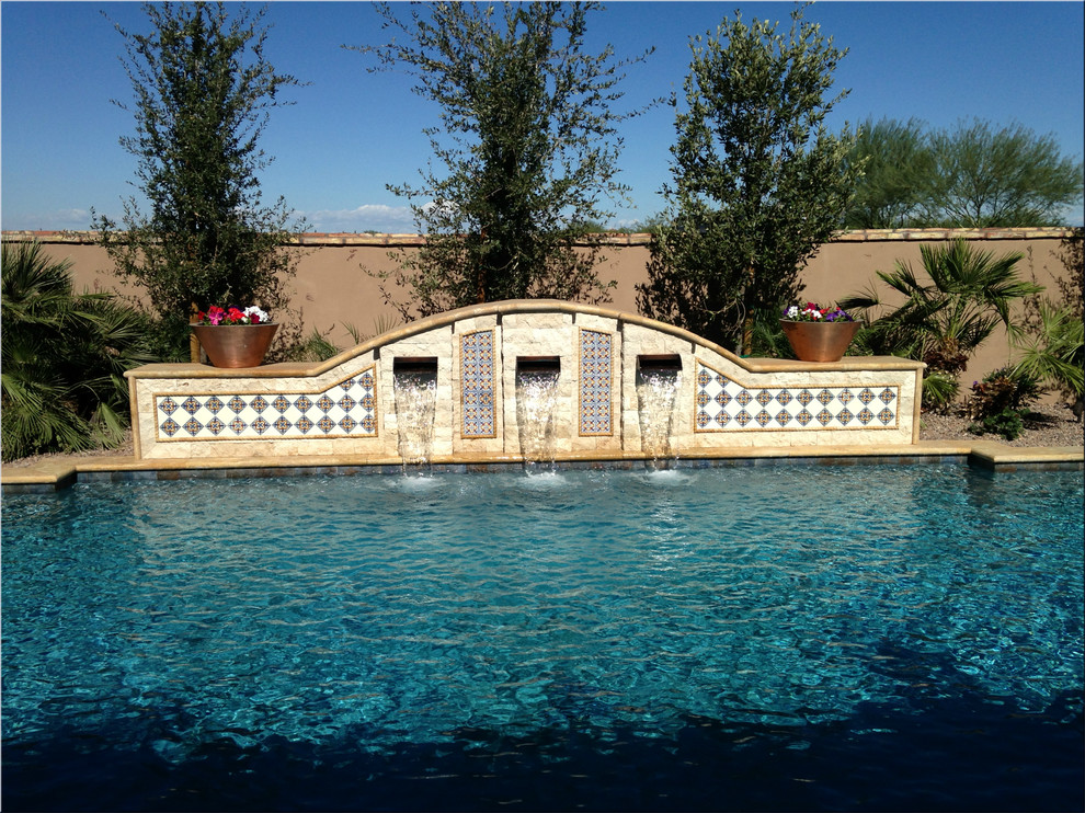 Mid-sized mediterranean backyard custom-shaped pool in Phoenix with a water feature and tile.
