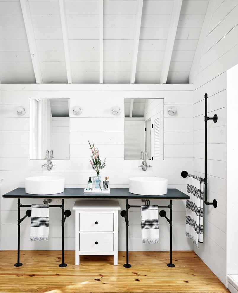 Inspiration for a mid-sized country bathroom in Austin with white cabinets, white walls, light hardwood floors and a vessel sink.