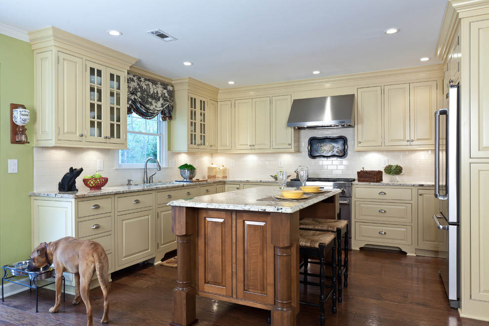 Expansive traditional u-shaped eat-in kitchen in Atlanta with an undermount sink, beaded inset cabinets, beige cabinets, granite benchtops, white splashback, porcelain splashback, stainless steel appliances, medium hardwood floors, with island, brown floor and white benchtop.