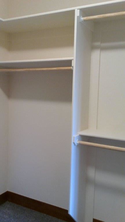 This is an example of a mid-sized contemporary gender-neutral walk-in wardrobe in Other with white cabinets and carpet.
