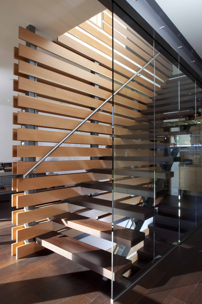 This is an example of a contemporary wood straight staircase in Vancouver with open risers and metal railing.