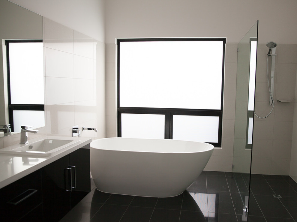 Large modern bathroom in Adelaide with black cabinets, a freestanding tub, an open shower, black tile, white walls and ceramic floors.