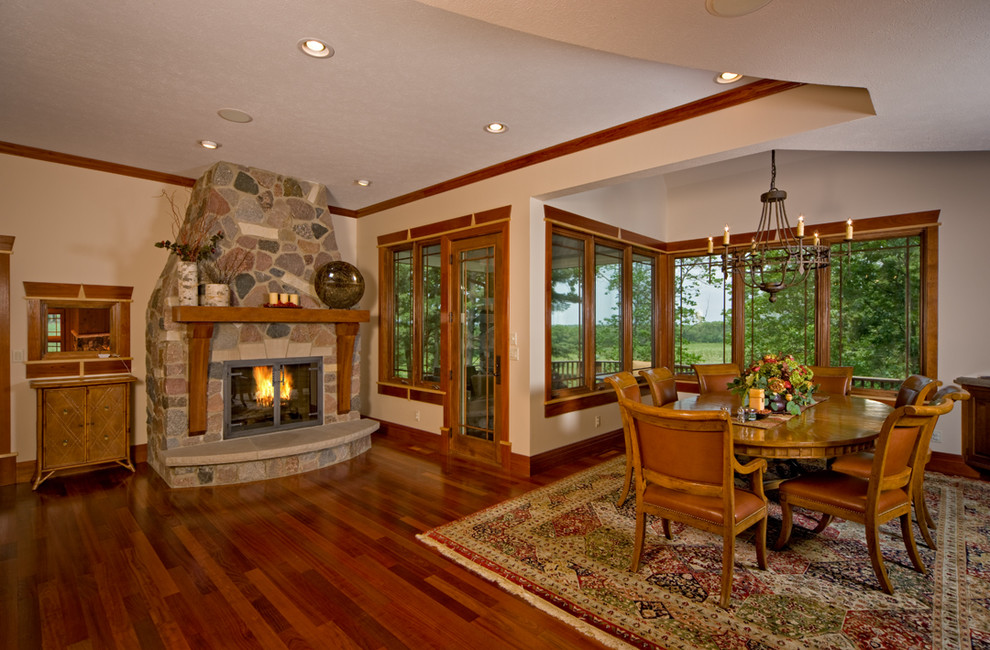 Photo of a mid-sized country open plan dining in Chicago with dark hardwood floors, a standard fireplace and a stone fireplace surround.