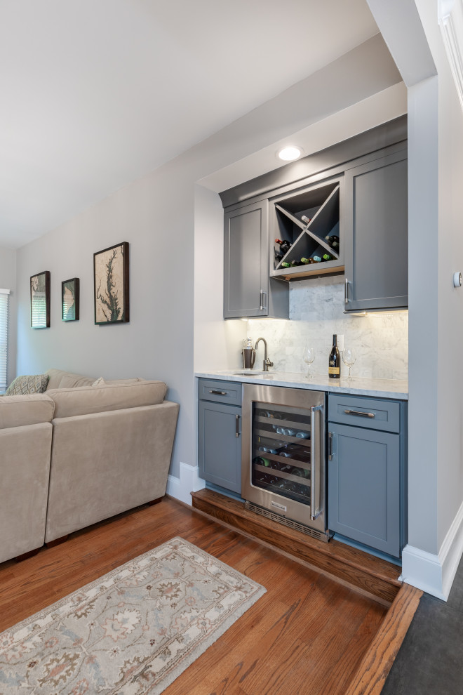 Foto på ett mellanstort funkis grå kök, med en undermonterad diskho, luckor med profilerade fronter, vita skåp, bänkskiva i kvartsit, vitt stänkskydd, rostfria vitvaror, en köksö och grått golv