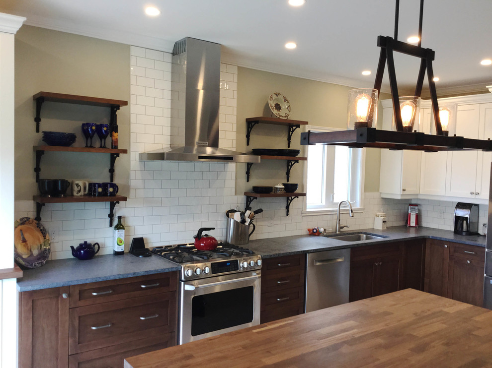 Inspiration for a mid-sized transitional l-shaped kitchen remodel in Ottawa with an undermount sink, shaker cabinets, dark wood cabinets, soapstone countertops, white backsplash, ceramic backsplash, stainless steel appliances and an island
