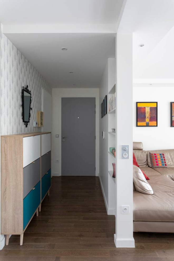 Esempio di un corridoio contemporaneo di medie dimensioni con pareti bianche, pavimento in legno massello medio, una porta singola, una porta grigia, pavimento marrone e carta da parati