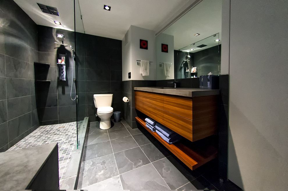 This is an example of a mid-sized contemporary master bathroom in Chicago with flat-panel cabinets, medium wood cabinets, a corner shower, an undermount sink, concrete benchtops, an open shower, a two-piece toilet, gray tile, slate, grey walls, grey floor and brown benchtops.