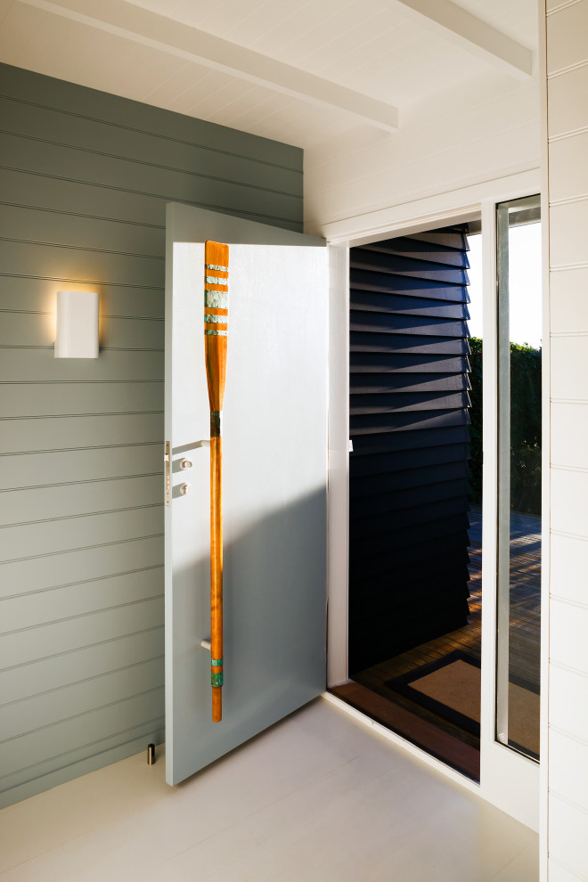 This is an example of a small beach style front door in Wellington with black walls, painted wood floors, a single front door, a blue front door, white floor, timber and planked wall panelling.