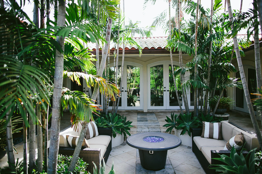 This is an example of a mid-sized mediterranean courtyard patio in Miami with an outdoor kitchen, natural stone pavers and a pergola.