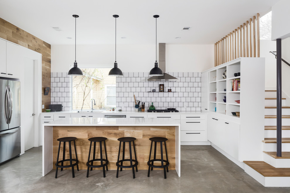 Mid-sized scandinavian open plan kitchen in Austin with flat-panel cabinets, white cabinets, white splashback, ceramic splashback, stainless steel appliances, concrete floors, with island, grey floor and white benchtop.