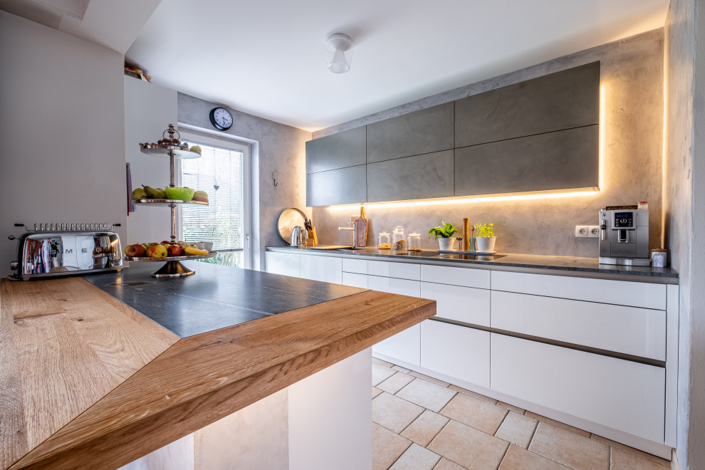 Foto på ett stort funkis grå kök, med en undermonterad diskho, granitbänkskiva, grått stänkskydd och en köksö