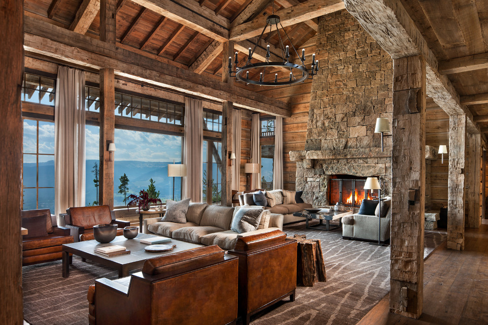 Photo of an expansive country open concept family room in Other with brown walls, medium hardwood floors, a standard fireplace, a stone fireplace surround and brown floor.