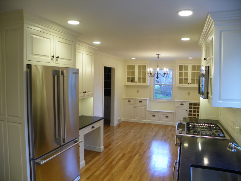 Example of a mid-sized transitional u-shaped light wood floor eat-in kitchen design in Boston with an undermount sink, beaded inset cabinets, white cabinets, quartz countertops, white backsplash, subway tile backsplash, stainless steel appliances and no island