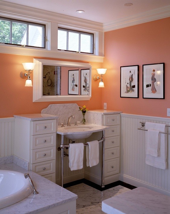 Photo of a mid-sized traditional master bathroom in Portland Maine with a pedestal sink, recessed-panel cabinets, white cabinets, marble benchtops, a drop-in tub, white tile, orange walls and marble floors.