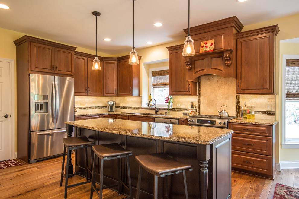 Mid-sized traditional l-shaped eat-in kitchen in Detroit with an undermount sink, raised-panel cabinets, medium wood cabinets, quartz benchtops, beige splashback, stone tile splashback, stainless steel appliances, medium hardwood floors and with island.