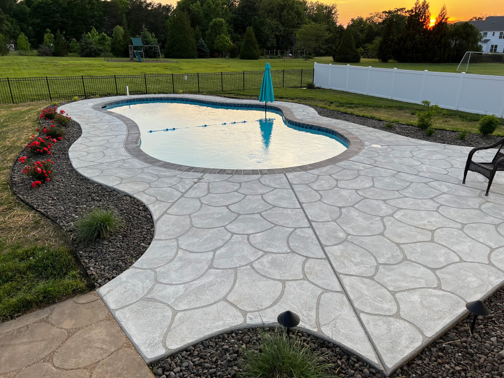 Photo of a mid-sized traditional backyard custom-shaped pool in DC Metro with concrete slab.