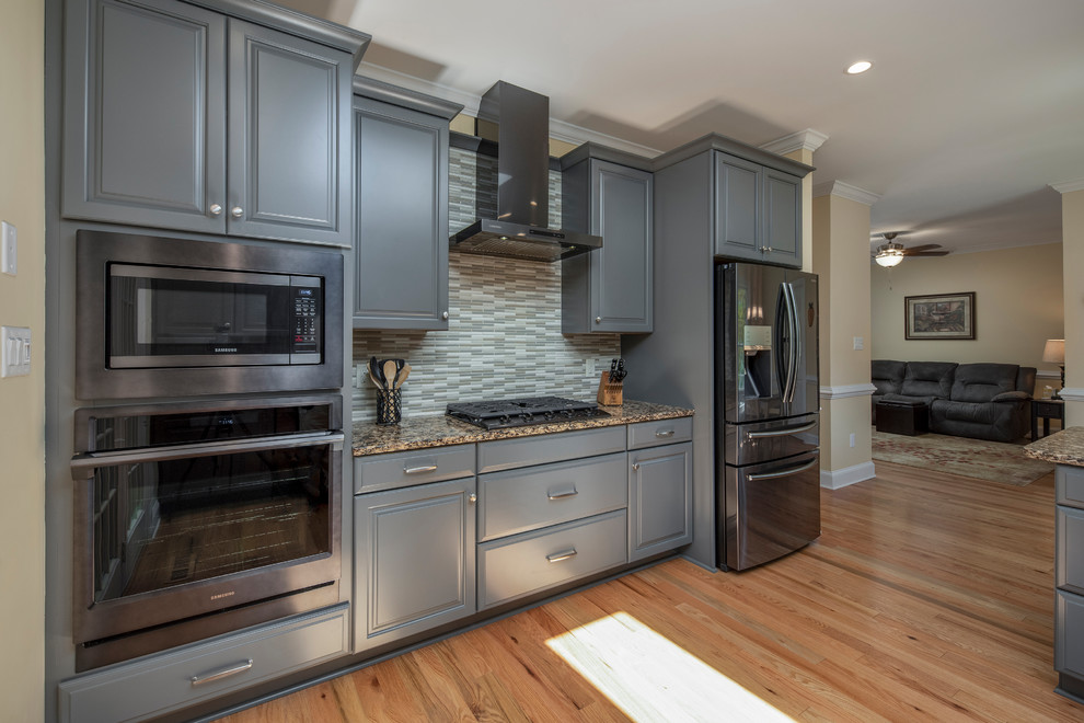 Kitchen - transitional kitchen idea with raised-panel cabinets, gray cabinets, granite countertops, black appliances, a peninsula and multicolored countertops