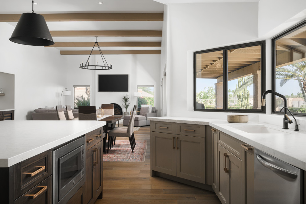 Inspiration for a large traditional l-shaped eat-in kitchen in Phoenix with an undermount sink, shaker cabinets, beige cabinets, white splashback, black appliances, medium hardwood floors, with island, brown floor, white benchtop and vaulted.