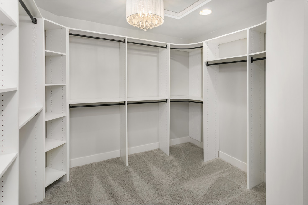 This is an example of a large transitional gender-neutral walk-in wardrobe in Seattle with carpet and grey floor.