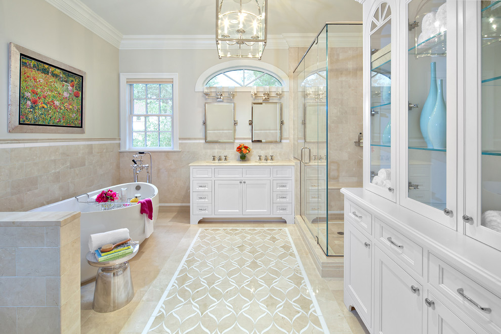 This is an example of a traditional master bathroom in New York with recessed-panel cabinets, white cabinets, a freestanding tub, a corner shower, beige walls, an undermount sink, beige floor and a hinged shower door.
