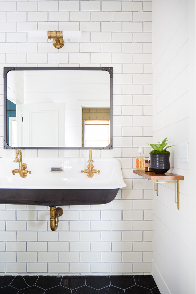 Photo of a country bathroom in Los Angeles with white tile, subway tile, white walls, a wall-mount sink and black floor.