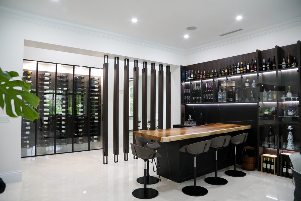 Inspiration for a contemporary l-shaped wet bar in Miami with a drop-in sink, glass-front cabinets, wood benchtops, black splashback, marble floors and white floor.