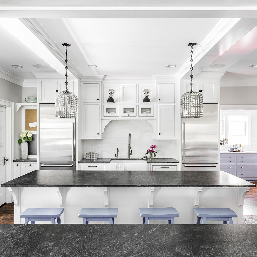 Inspiration for a transitional single-wall kitchen in Chicago with a farmhouse sink, shaker cabinets, white cabinets, white splashback, subway tile splashback, stainless steel appliances, medium hardwood floors, with island and brown floor.
