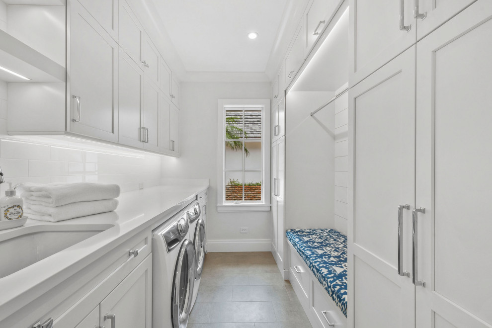 Exempel på en stor klassisk vita vitt tvättstuga, med en undermonterad diskho, luckor med profilerade fronter, vita skåp, bänkskiva i kvartsit, vitt stänkskydd, stänkskydd i sten, ljust trägolv och brunt golv