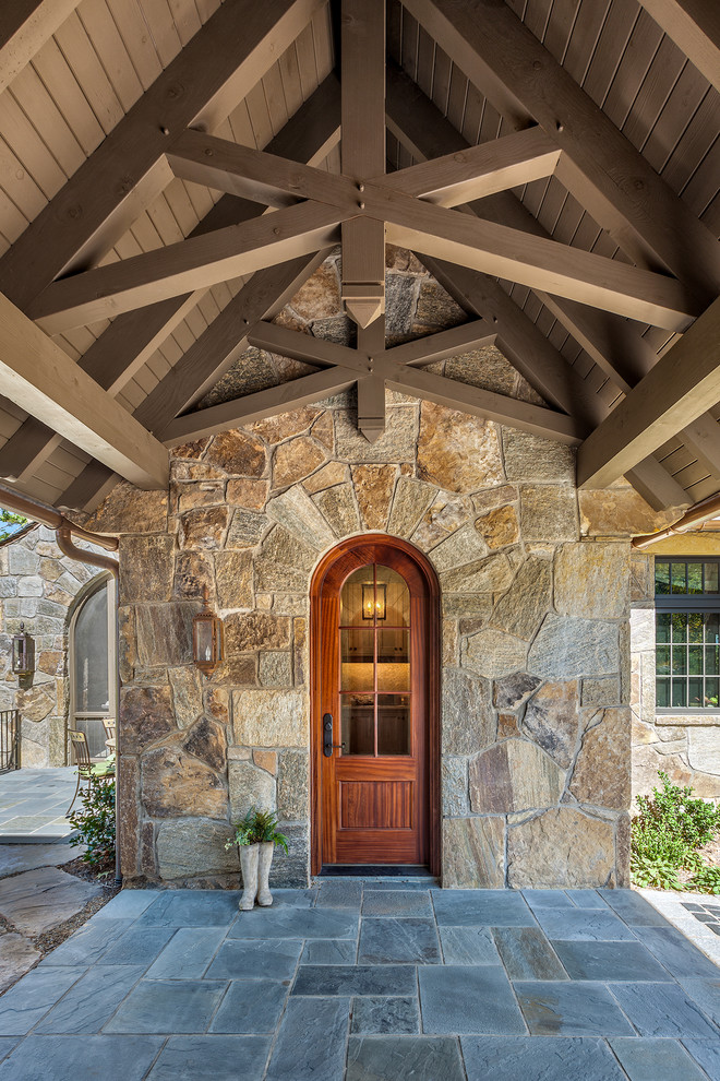 Inspiration for a large rustic stone slate floor front door remodel with brown walls and a medium wood front door