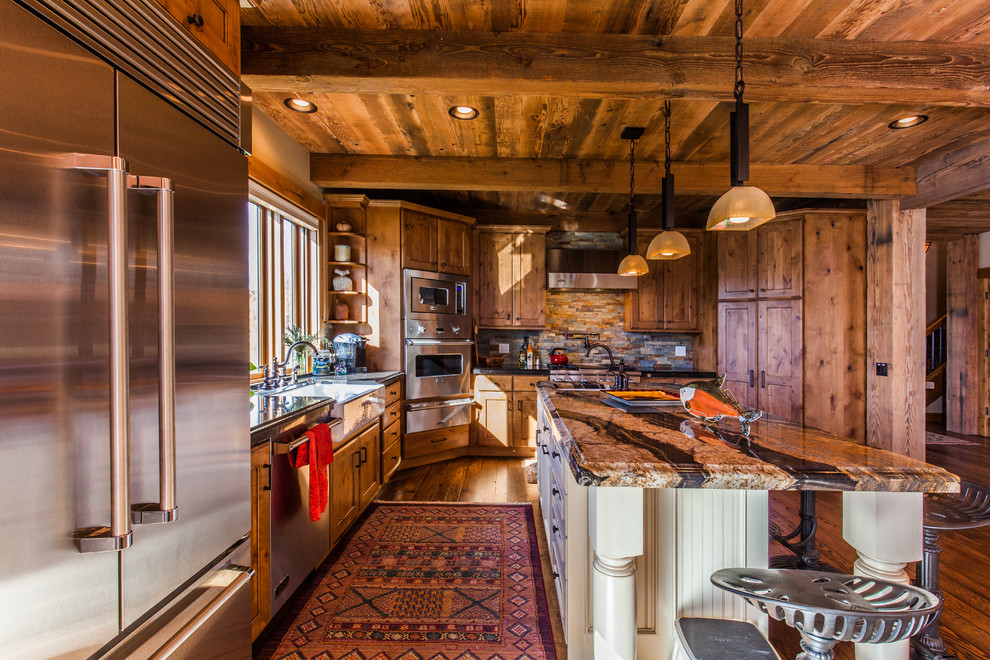 Example of a mid-sized mountain style l-shaped dark wood floor open concept kitchen design with a farmhouse sink, shaker cabinets, medium tone wood cabinets, granite countertops, multicolored backsplash, stone tile backsplash, stainless steel appliances and an island