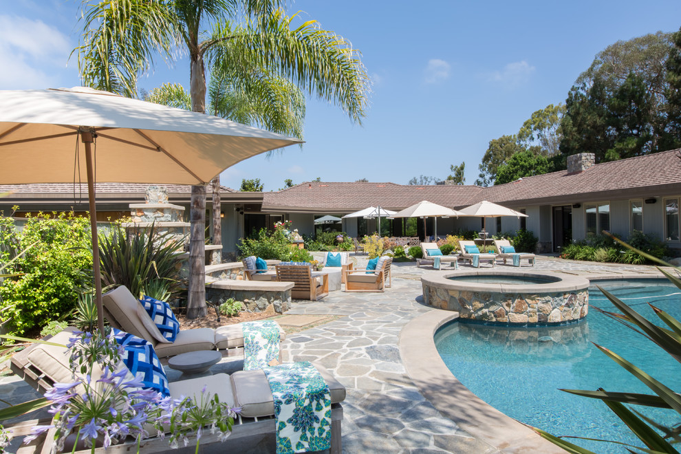 Large trendy backyard stone patio photo in Los Angeles with an awning