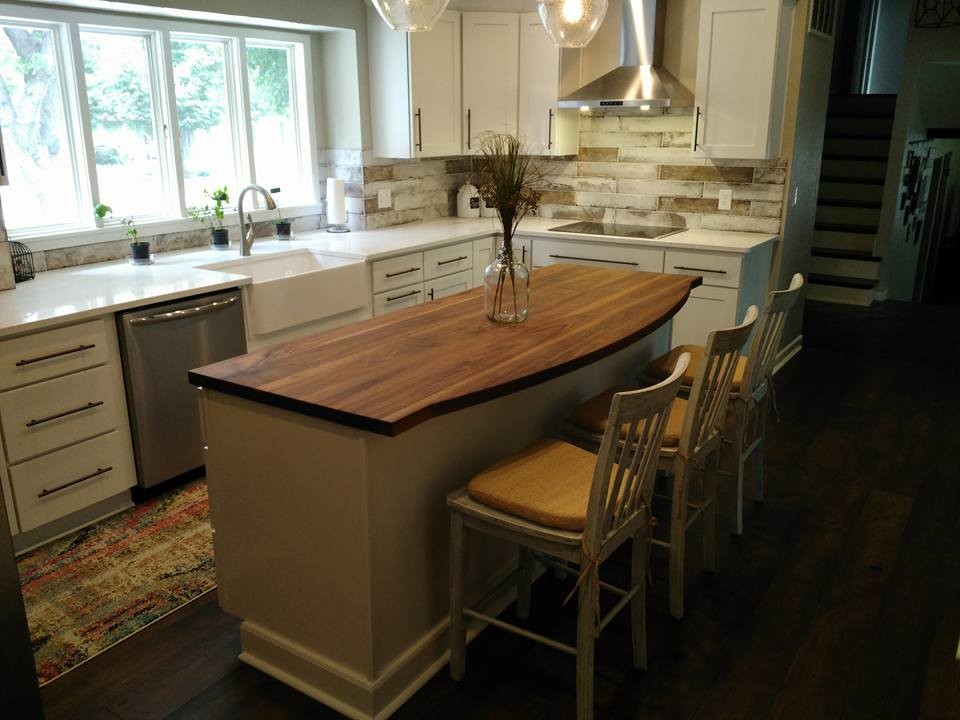Example of a mid-sized transitional l-shaped dark wood floor and brown floor eat-in kitchen design with a farmhouse sink, shaker cabinets, white cabinets, wood countertops, gray backsplash, marble backsplash, stainless steel appliances and an island