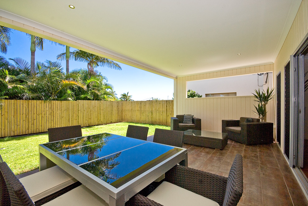 Design ideas for a mid-sized beach style backyard patio in Brisbane with tile and a roof extension.