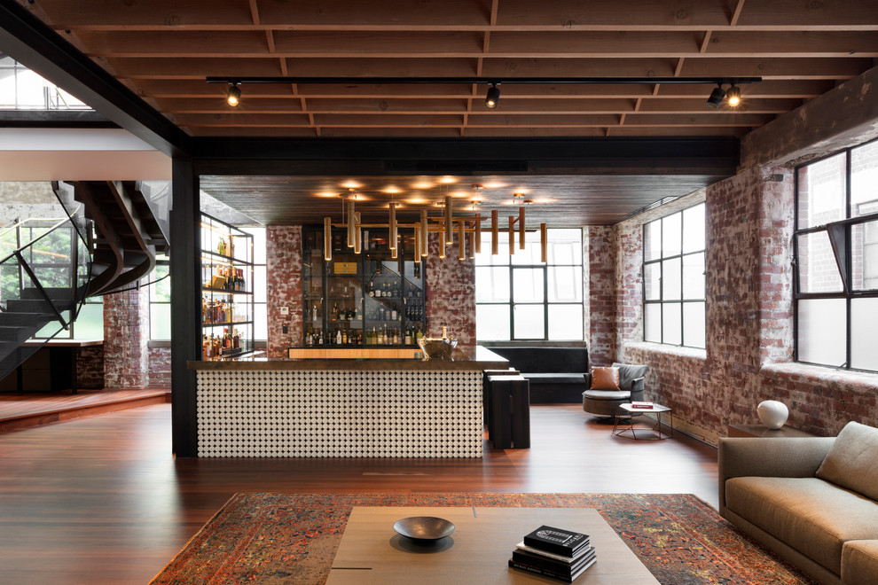 This is an example of a mid-sized industrial u-shaped seated home bar in Melbourne with an undermount sink, glass-front cabinets, light wood cabinets, onyx benchtops, brick splashback, medium hardwood floors, brown floor and brown benchtop.